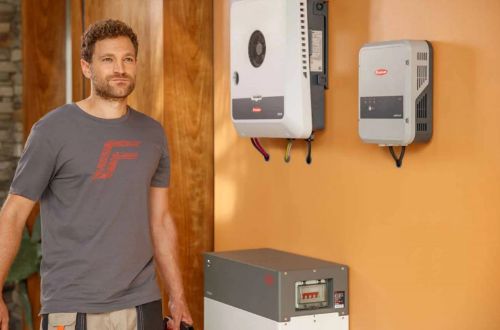 Installer with Fronius commercial inverters mounted outside