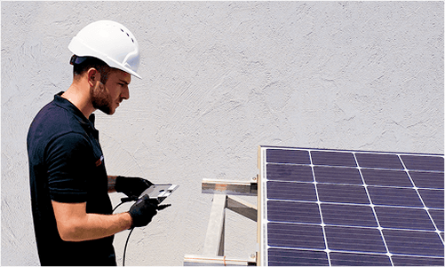 Worker installing power optimizer on solar panel